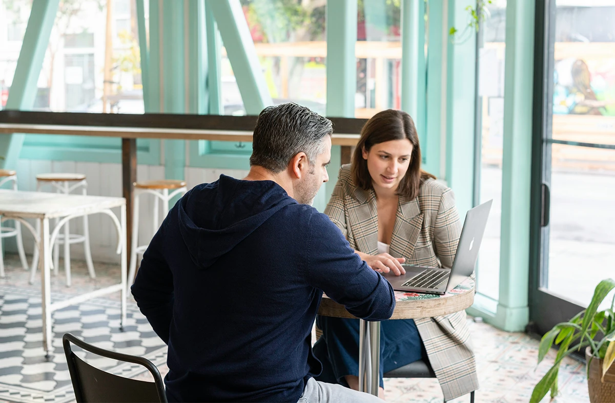 A middle-aged couple is having a meeting looking at their laptop.